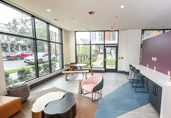 Modern community space with large windows, comfy seating, and workspace area at Park Morton.